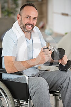 disabled man in wheelchair adds weight to dumbbell