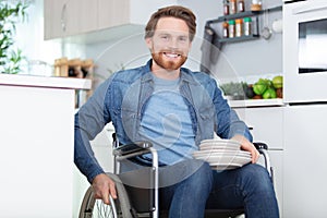 disabled man wheelchair carrying dishes in kitchen