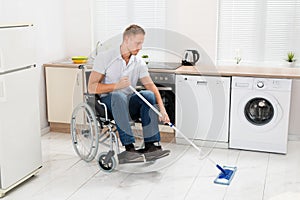 Disabled man on wheelchair cleaning floor