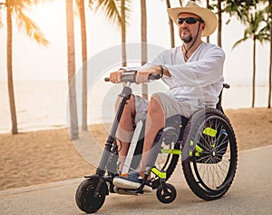 Disabled man in a wheelchair with electric scooter on the beach