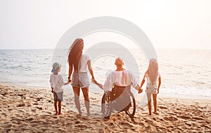 Disabled man in a wheelchair with his family on the beach.