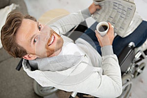 disabled man in wheelchair holding coffee and newspaper photo