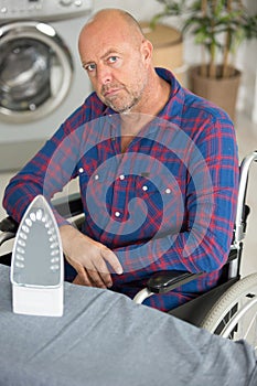 Disabled man on wheelchair ironing clothing