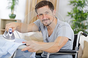 Disabled man on wheelchair ironing clothing