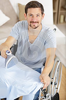 disabled man in wheelchair ironing clothing