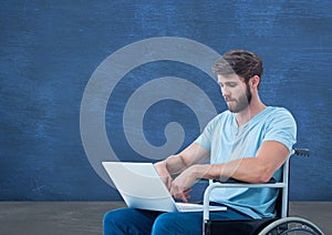 Disabled man in wheelchair on laptop in front of blackboard