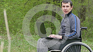 Disabled man wheelchair with a laptop in wheelchair working on nature green