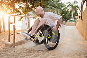 Disabled man in a wheelchair moves on a ramp to the beach.