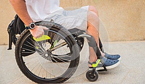 Disabled man in a wheelchair moves on a ramp to the beach.