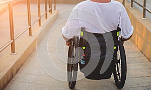 Disabled man in a wheelchair moves on a ramp to the beach.