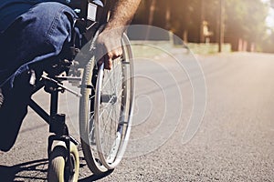 Disabled man on wheelchair in the outdoor park like other people, Close-Up his wheel