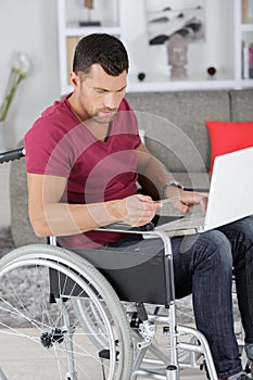 Disabled man in wheelchair typing on laptop