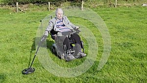 Disabled man wheelchair user metal detecting coins a field