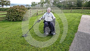 Disabled man Wheelchair user metal detecting for coins field