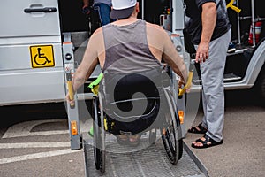 Disabled man on wheelchair using accessible vehicle with lift mechanism.