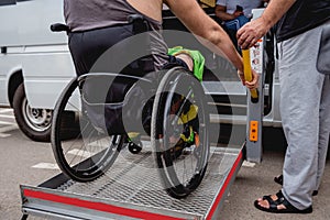 Disabled man on wheelchair using accessible vehicle with lift mechanism.