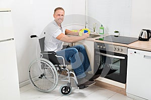 Disabled man on wheelchair washing dishes