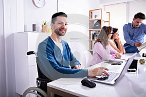 Disabled Man On Wheelchair Working In Office