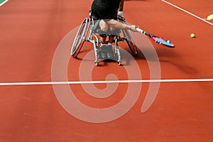 Disabled mature man on a wheelchair playing tennis on an indoor tennis court. Copy space