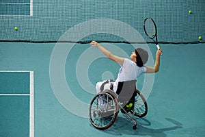 Disabled mature woman on wheelchair playing tennis on tennis court