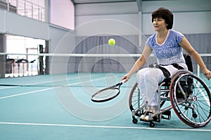 Disabled mature woman on wheelchair playing tennis on tennis court