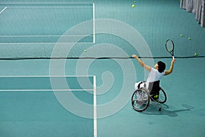 Disabled mature woman on wheelchair playing tennis on tennis court.
