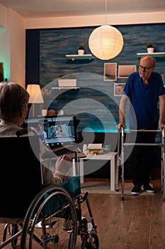 Disabled old woman holding laptop with video call