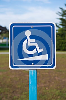 Disabled parking signage on the pole in blue and white colour in outdoors.