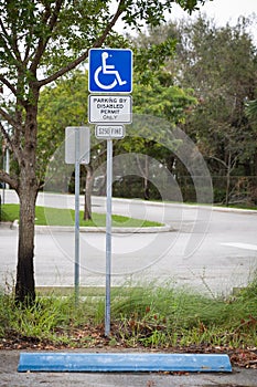 Disabled parking space, wheelchair sign, symbols and fine notice on the parking place in the park