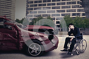 Disabled person with damaged car looks sad