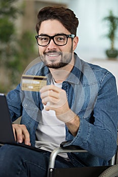 Disabled person holds credit card and uses pc