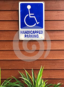 Disabled person parking sign on wooden wall. Blue sign `Handicapped parking`