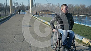 Disabled person rides to embankment along sea on wheel chair, portrait