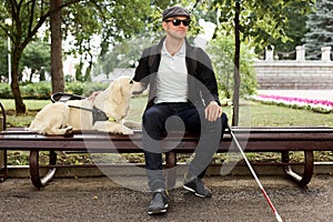 Disabled person sit having rest with dog guide outdoors