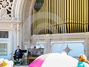 Disabled person sitting on wheelchair sings on stage with organ