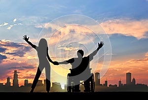 Disabled person in wheelchair with girlfriend on background of city