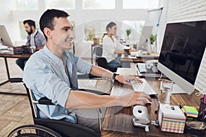 Disabled person in the wheelchair works in the office at the computer.