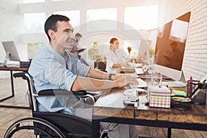 Disabled person in the wheelchair works in the office at the computer.