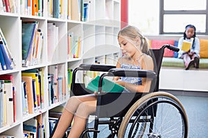 Disabled school girl reading book in library