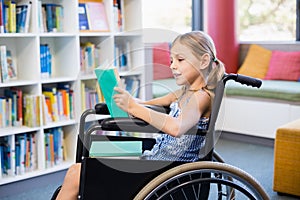 Disabled school girl reading book in library