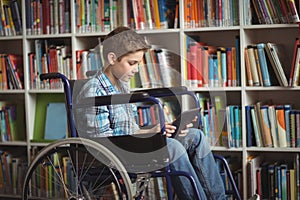 Disabled schoolboy using digital tablet in library