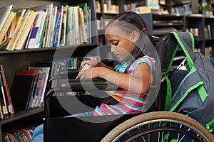 Disabled schoolgirl reading a book in the classroom