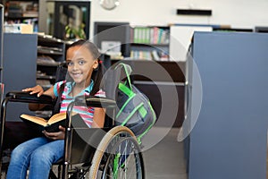 Disabled schoolgirl reading a book in the classroom