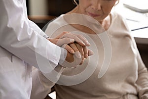 Disabled senior female hand in palms of young woman medic