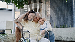 Disabled senior grandpa on wheelchair with grandchild and mother in park