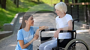 Disabled senior lady in wheelchair smiling to volunteer, communication support