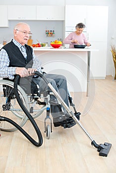 Disabled senior man cleaning while wife cooking