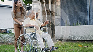 Disabled senior man on wheelchair with daughter in park