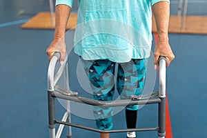 Disabled senior woman walking with walker in sports center