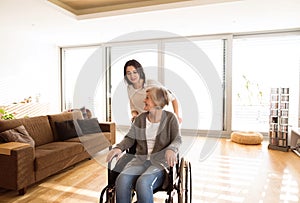 Disabled senior woman in wheelchair with her young daugher.